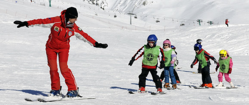 Instruktr i skidskola som instruerar en liten grupp barn